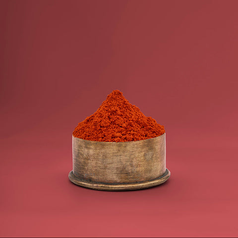Red chilli powder in a small container on a red background