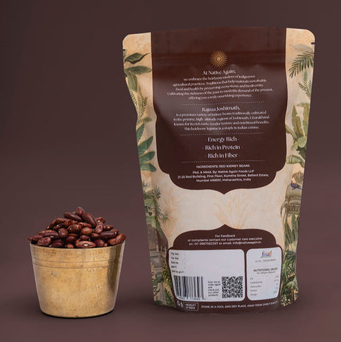 Coffee beans in a small container next to a coffee bag on a brown background