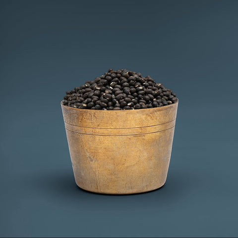 Wooden bowl filled with black beans on a dark blue background