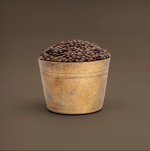 Wooden barrel filled with coffee beans on a brown background